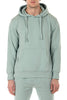 Person wearing a light green hoodie and pants on a white background