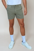 Person wearing olive green shorts and white sneakers on a plain background