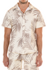 Man wearing a beige and brown leaf pattern shirt and pants on a white background