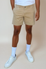 Person wearing beige shorts, white socks, and white sneakers on a beige background