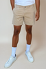Person wearing beige shorts, white socks, and white sneakers on a plain background