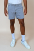 Person wearing light gray shorts, white sneakers, and light blue socks on a beige background