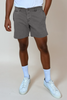 Person wearing gray shorts, white socks, and white sneakers on a beige background