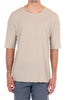 Man wearing a beige t-shirt and blue pants on a white background